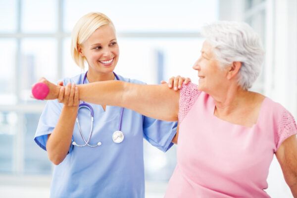 Doctor Assisting Senior Patient In Lifting Dumbbell